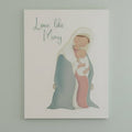 Print with illustration of Mary holding baby Jesus on a white surface