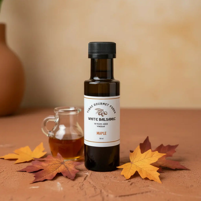 Maple White Balsamic Vinegar bottle with maple syrup and maple leaves on terracotta surface