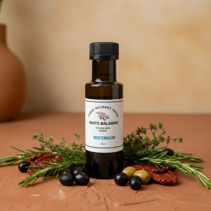 Mediterranean White Balsamic Vinegar bottle with herbs and olives on terracotta surface