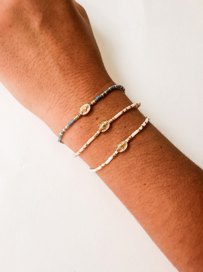 Three bracelets on a person's wrist against a white background