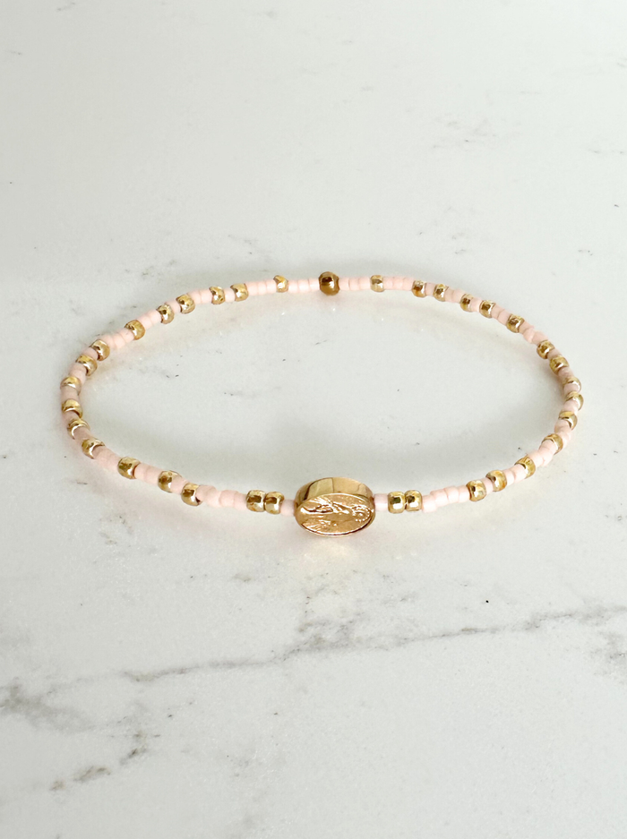Bracelet with pink beads and gold accents on a marble surface