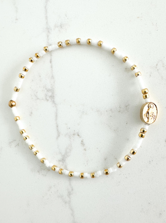 Beaded necklace with gold and white beads on a marble surface