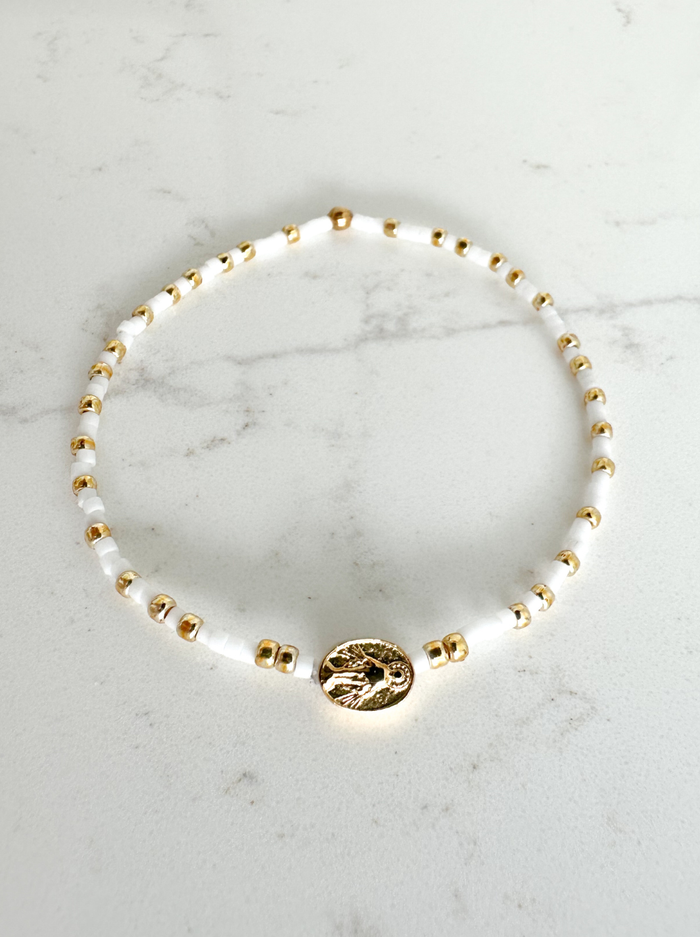 Bracelet with gold and white beads on a marble surface
