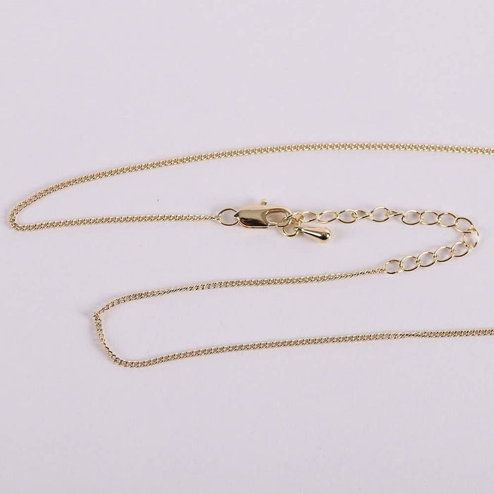 Gold chain necklace on a light gray background