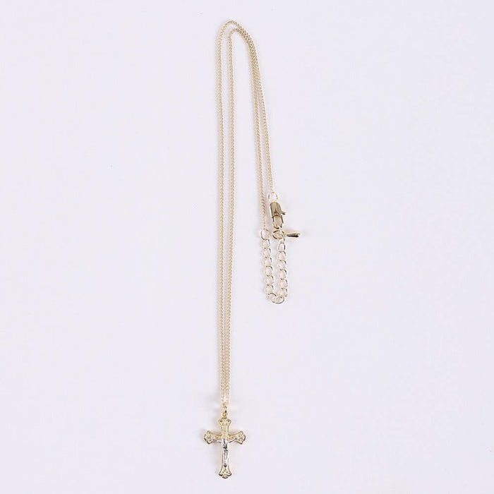 Gold chain necklace with a cross pendant on a light gray background