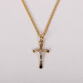 Gold cross necklace with chain on a light gray background
