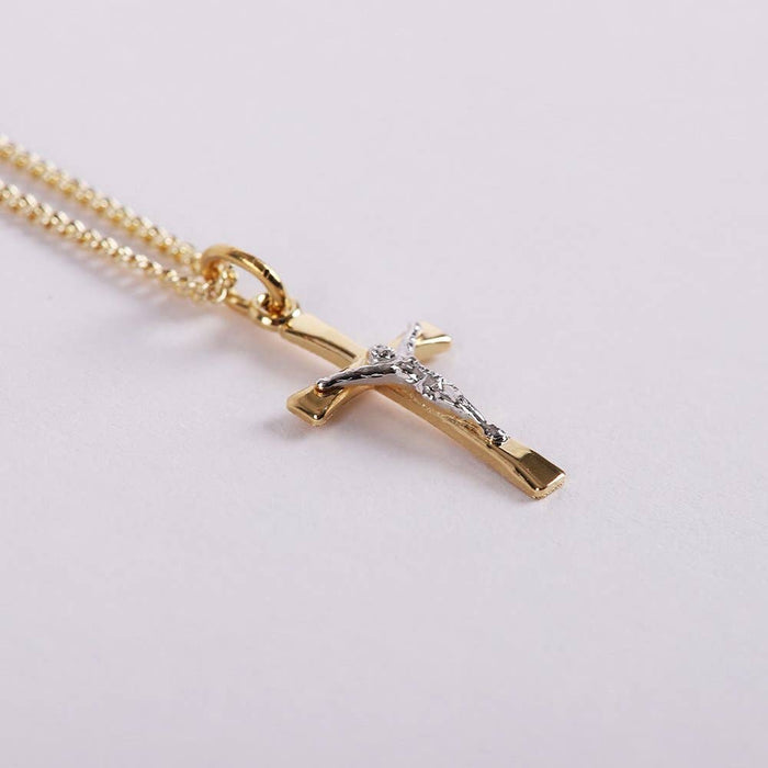 Gold necklace with a cross pendant on a light gray background