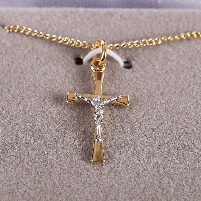 Gold and silver crucifix pendant on a chain against a gray background
