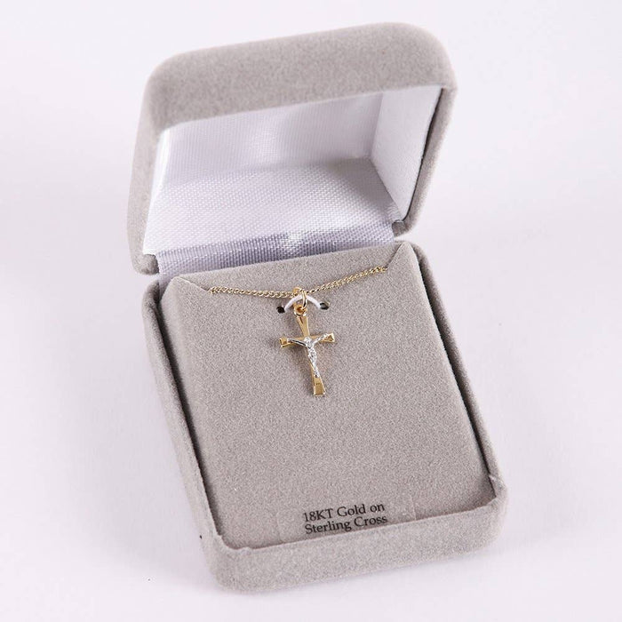 Gold cross necklace in a gray jewelry box on a white background