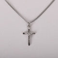 Silver crucifix pendant on a chain against a light gray background