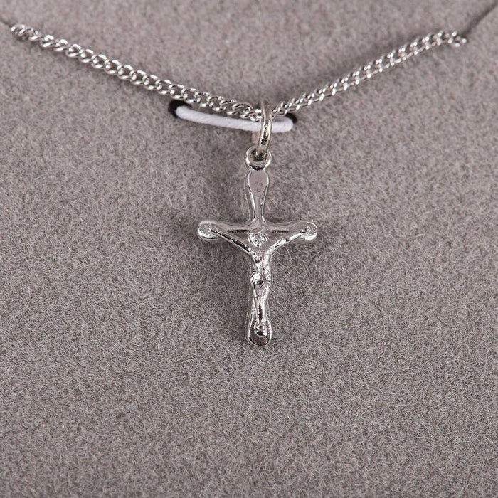 Silver crucifix pendant on a chain against a gray background
