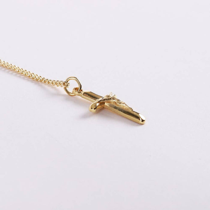 Gold necklace with a cross pendant on a light gray background