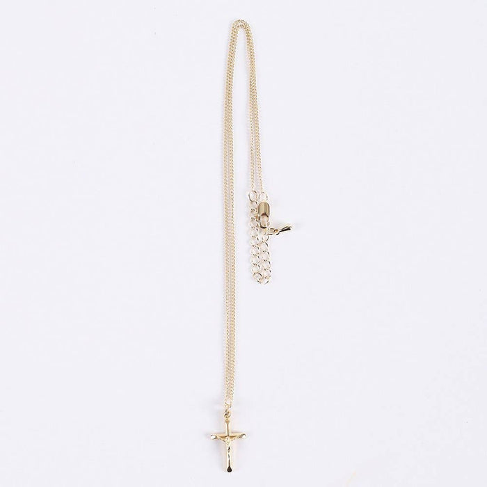 Gold necklace with a cross pendant on a light gray background