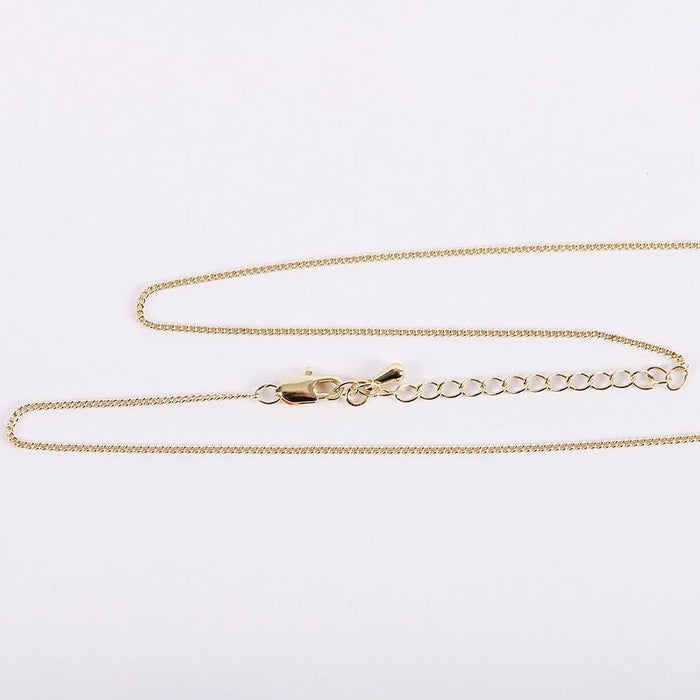 Gold chain necklace on a light gray background