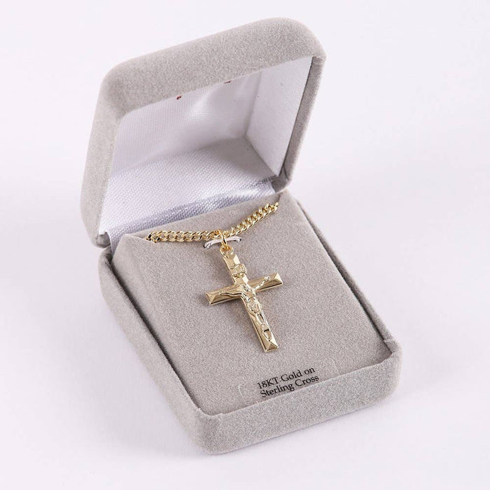 Gold cross necklace in a gray jewelry box on a white background