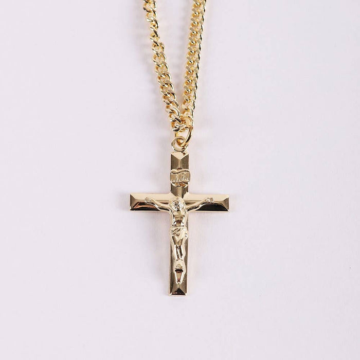 Gold crucifix pendant on a chain against a light purple background