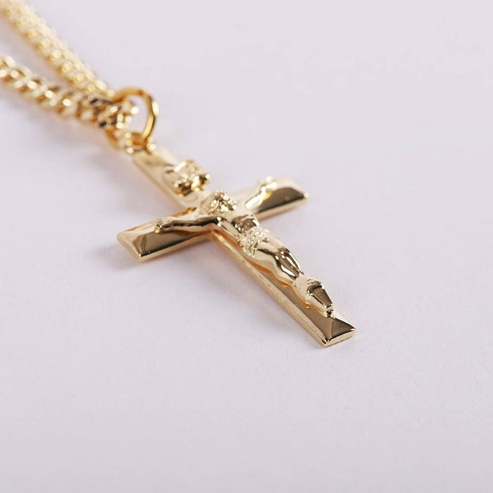 Gold cross pendant necklace on a light gray background