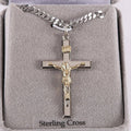 Silver crucifix necklace with gold accents on a gray cushion