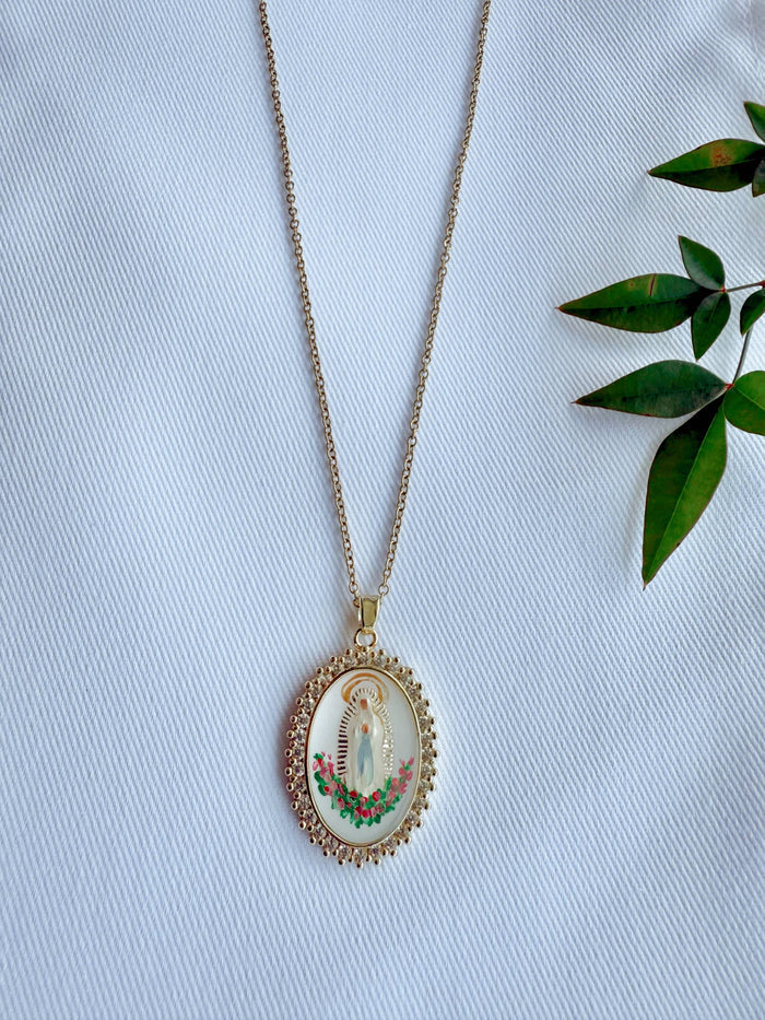 Necklace with a pendant featuring a religious design on a light blue fabric background.