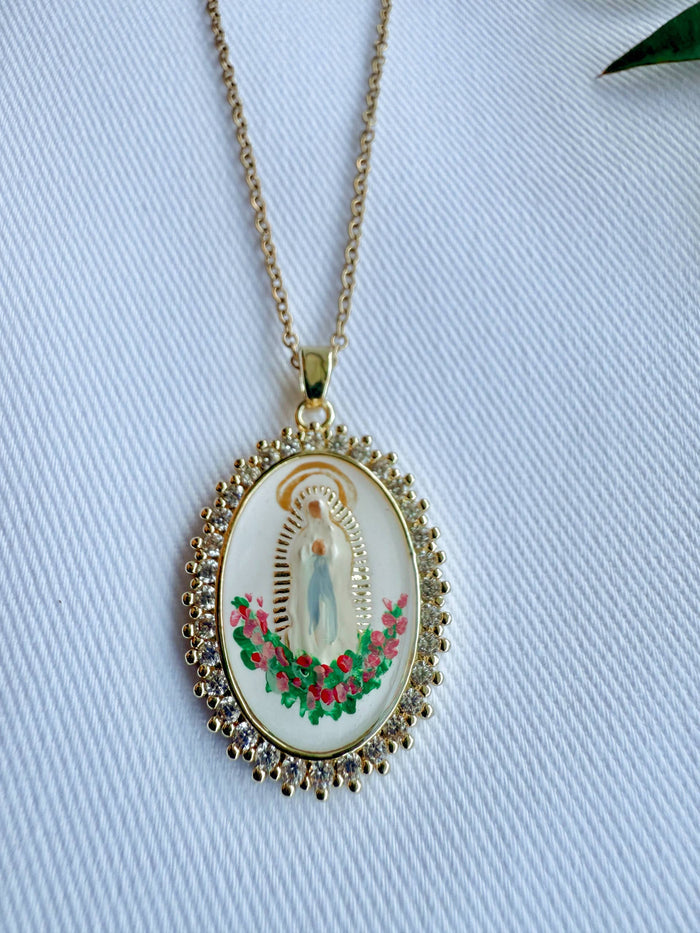 Gold necklace with a religious pendant on a light blue fabric background