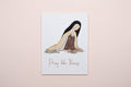 Print with illustration of st. Therese and text 'Pray like Therese' on a white surface.