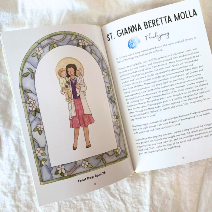 Open book with illustration of a saint and text on a white fabric background