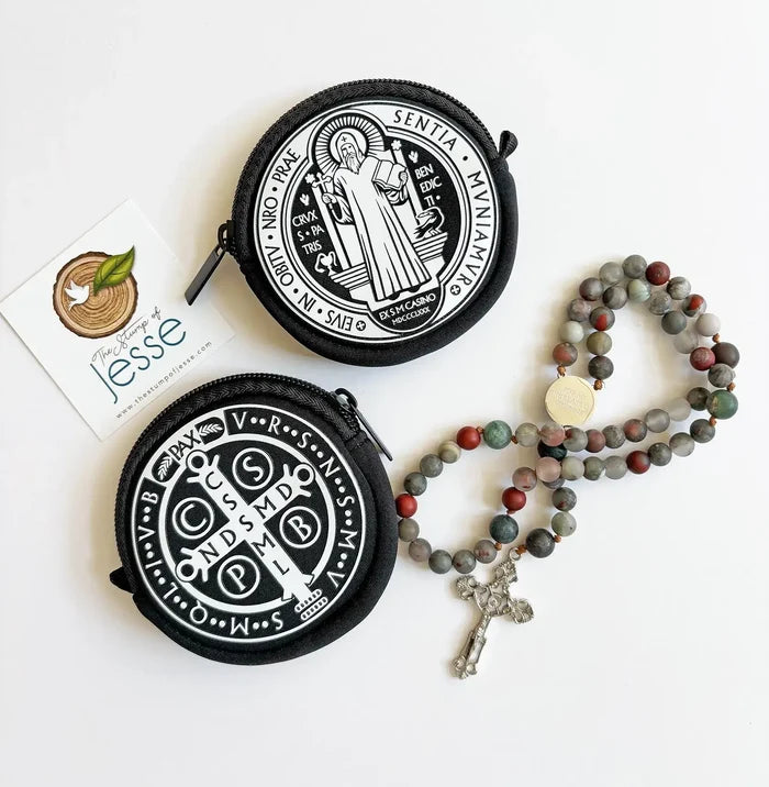 Two round black pouches with white designs and a rosary on a white background.