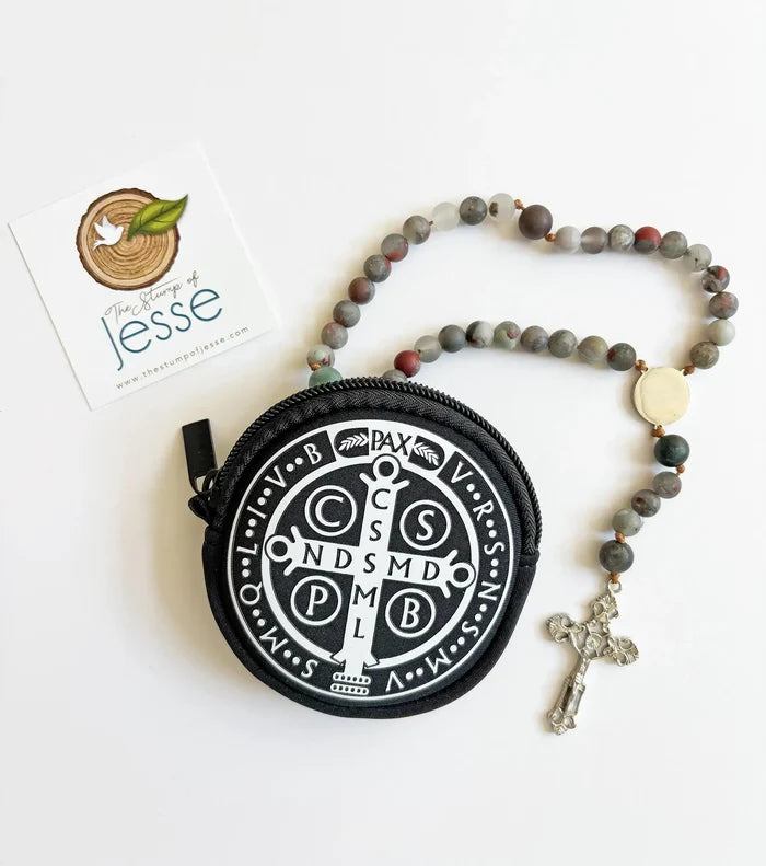 Round black pouch with white emblem and rosary on a white background