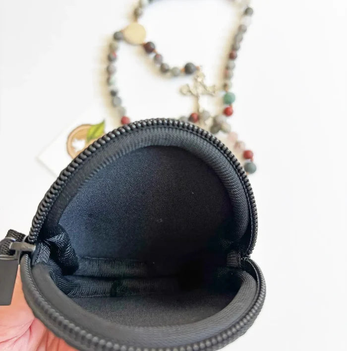Black zippered pouch held open by a hand with a blurred background