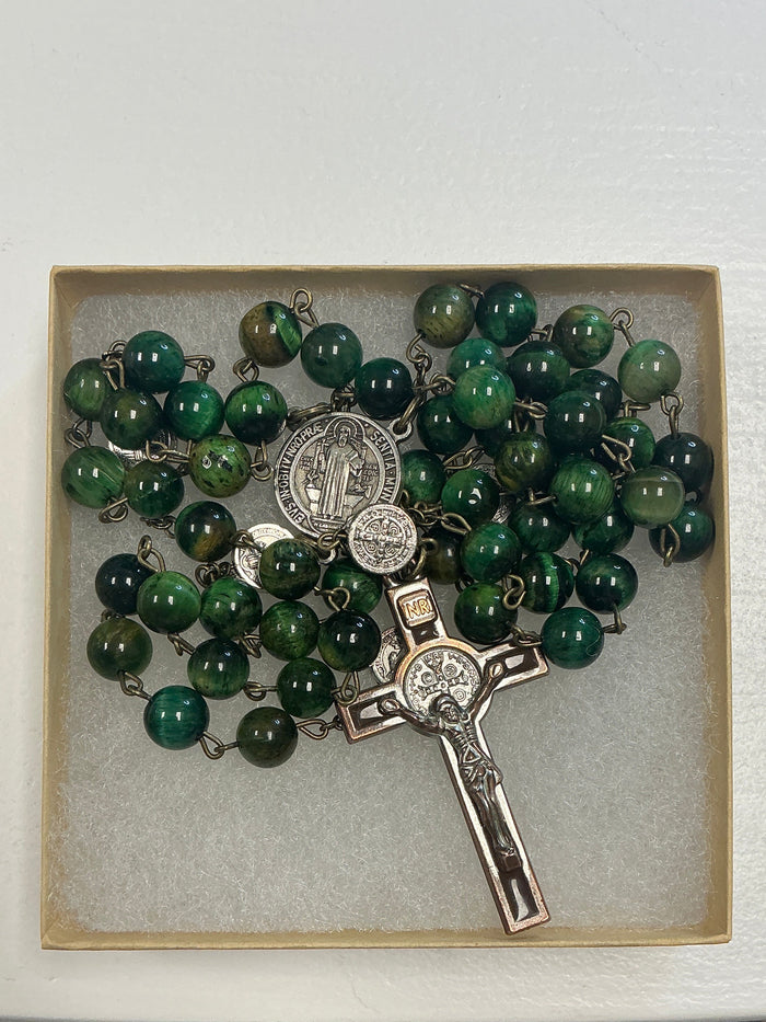 Green rosary in a wooden box on a white surface with a white background.