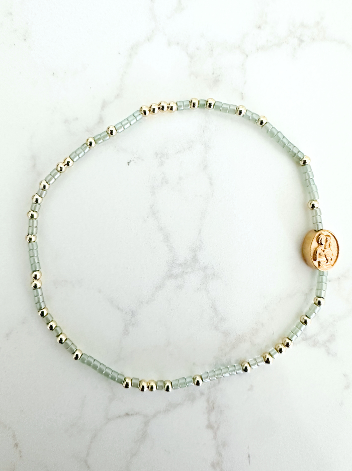Beaded bracelets with gold accents on a marble background
