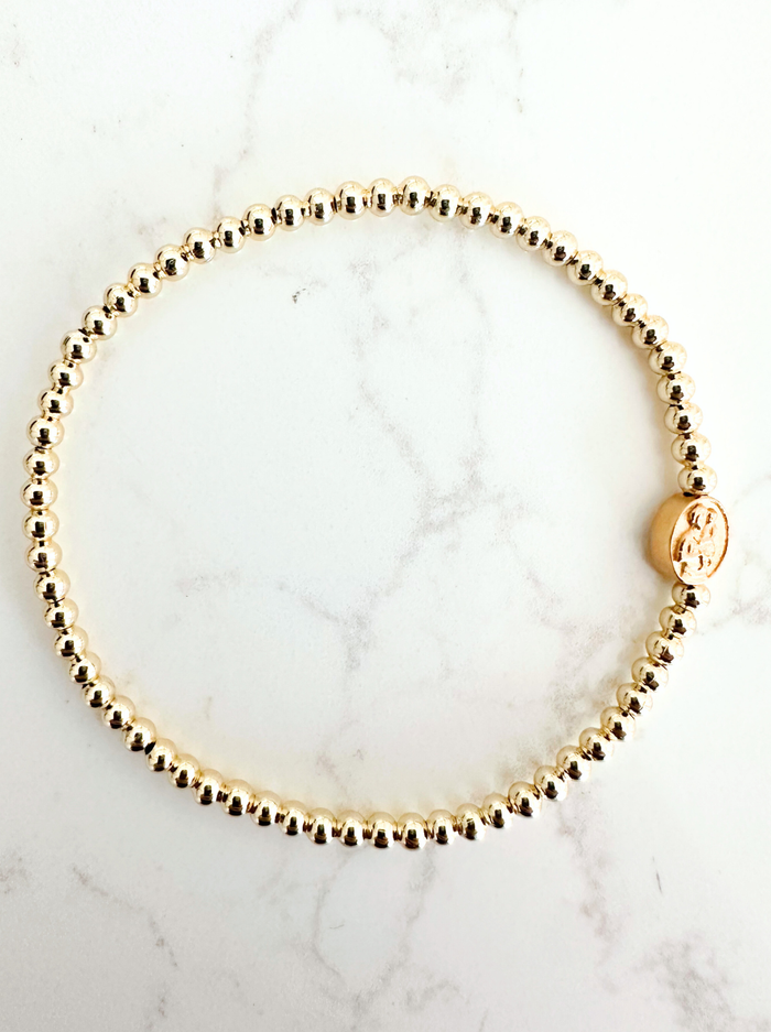 Gold beaded bracelet on a marble surface