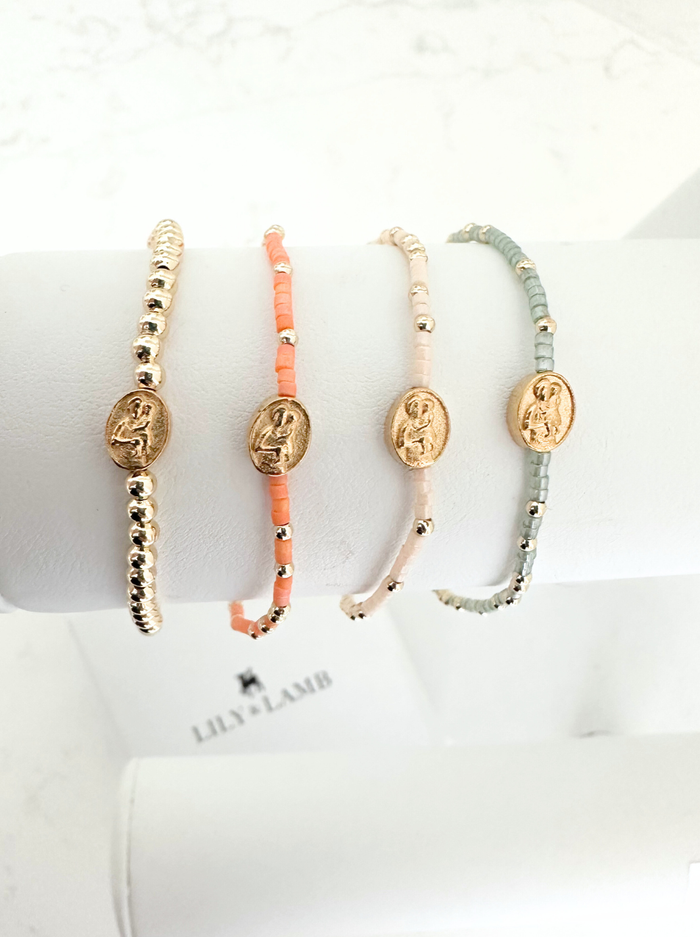 Four beaded bracelets with gold accents on a white surface, featuring the brand 'Lily & Lain'.