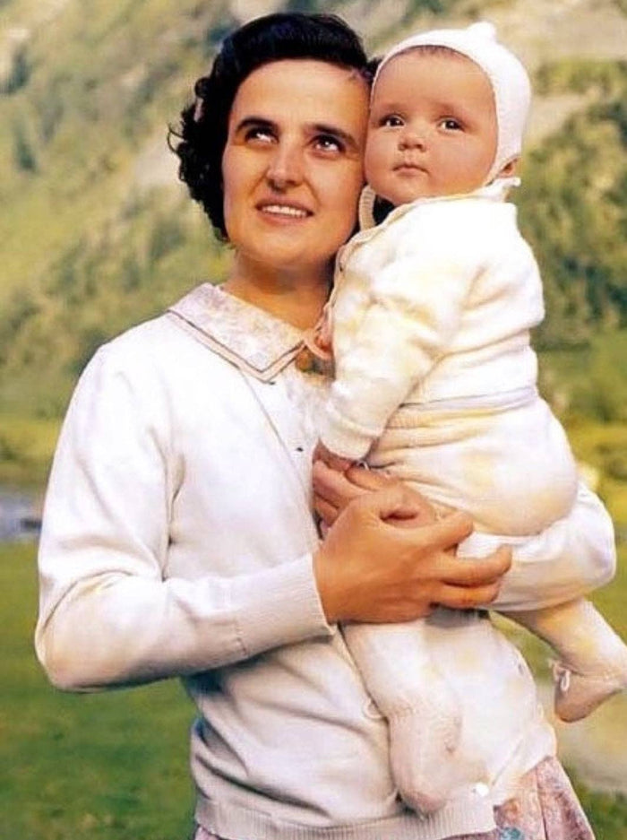 Woman holding a baby outdoors with a natural background