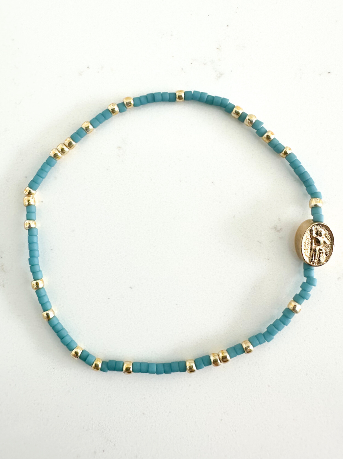 Turquoise beaded bracelet with gold accents on a white background
