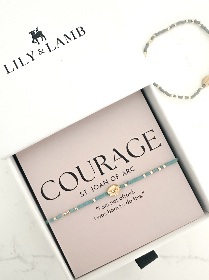 Bracelet on a box with 'Lily & Lamb' branding and text about courage.