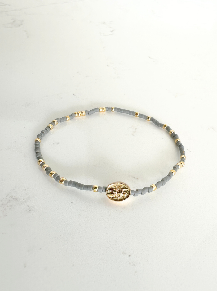 Bracelet with gray beads and gold accents on a light gray background