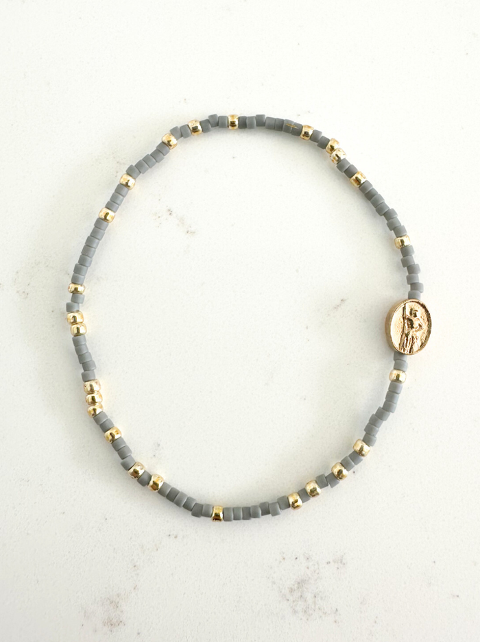 Gray beaded bracelet with gold accents on a light gray background