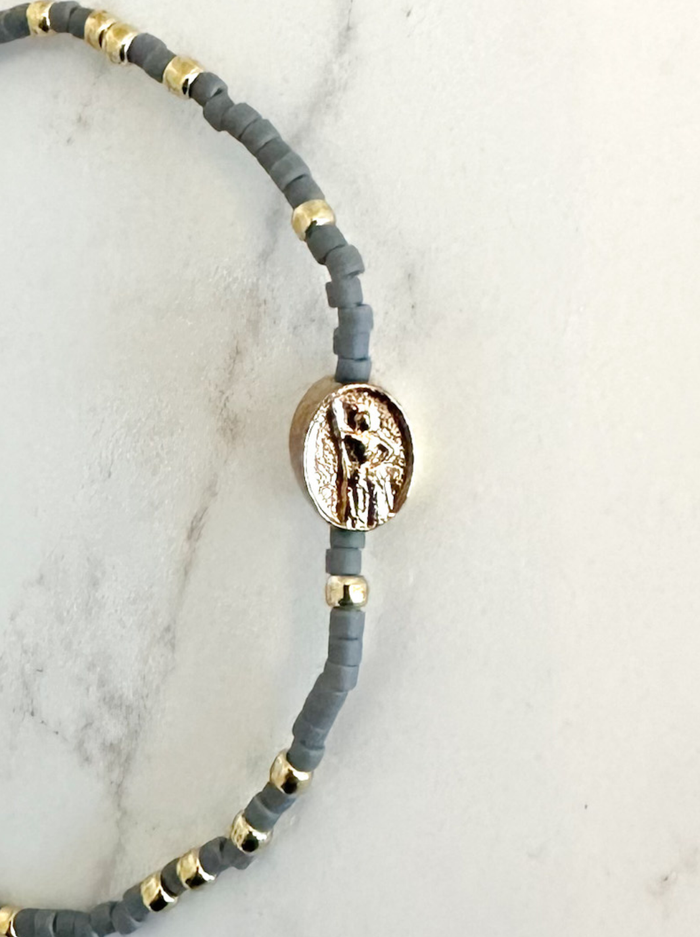 Bracelet with gray beads and gold accents on a marble surface