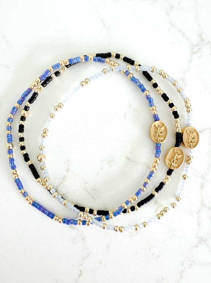 Set of beaded bracelets with coins on a marble surface