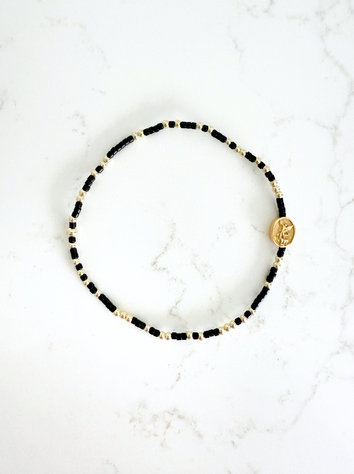 Bracelet with black and gold beads on a white marble surface