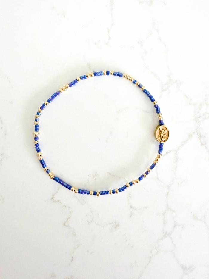 Bracelet with blue and gold beads on a white marble surface