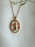 Gold necklace with a pendant featuring a religious design on a white background