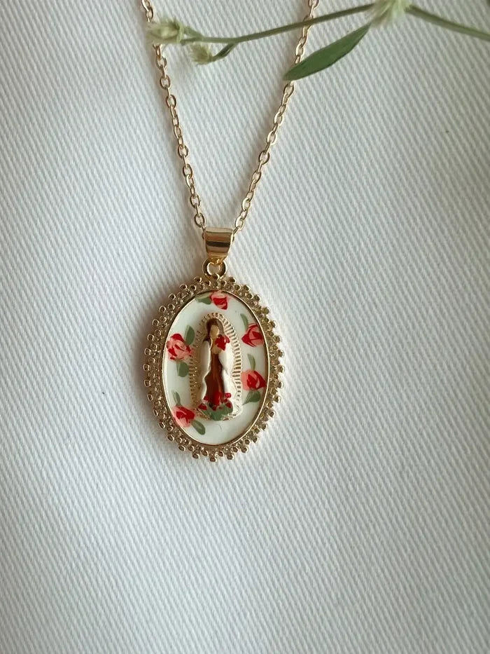 Gold necklace with a pendant featuring a religious design on a white background