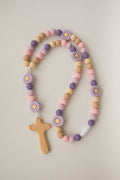 Pastel-colored beaded necklace with wooden cross and flower decorations on a light background