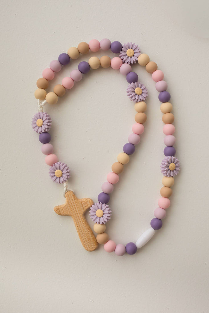 Rosary with pastel beads and wooden cross on a light background