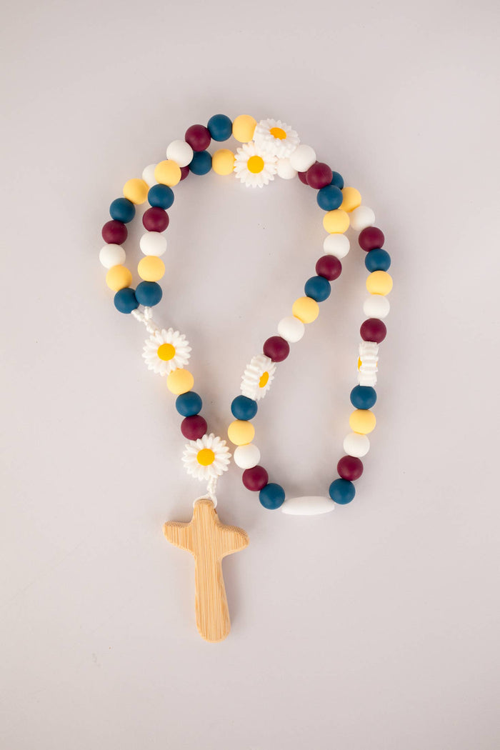 Colorful beaded rosary with wooden cross on a light gray background