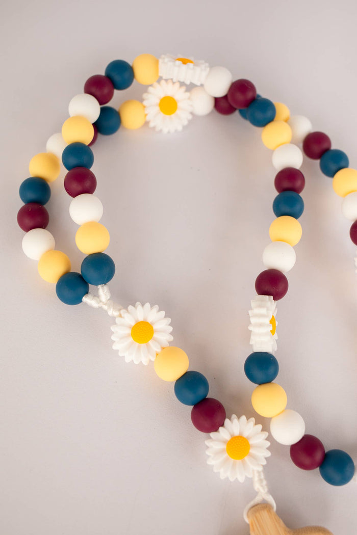 Colorful beaded rosary with flower-shaped beads on a light gray background