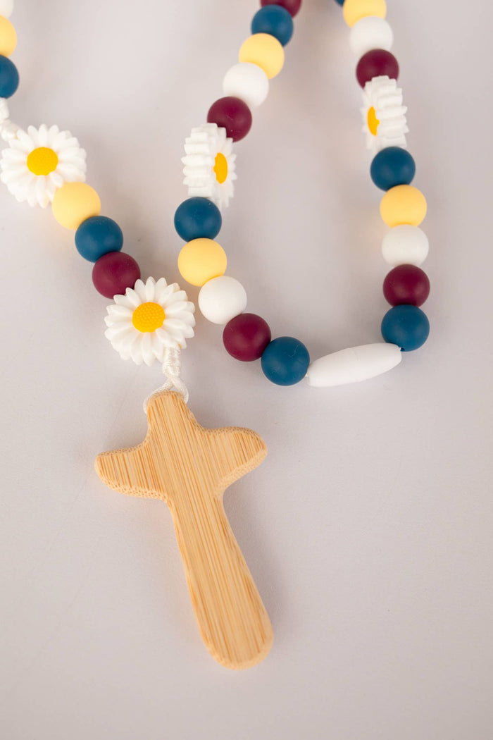 Rosary with colorful beads and a wooden cross on a light gray background