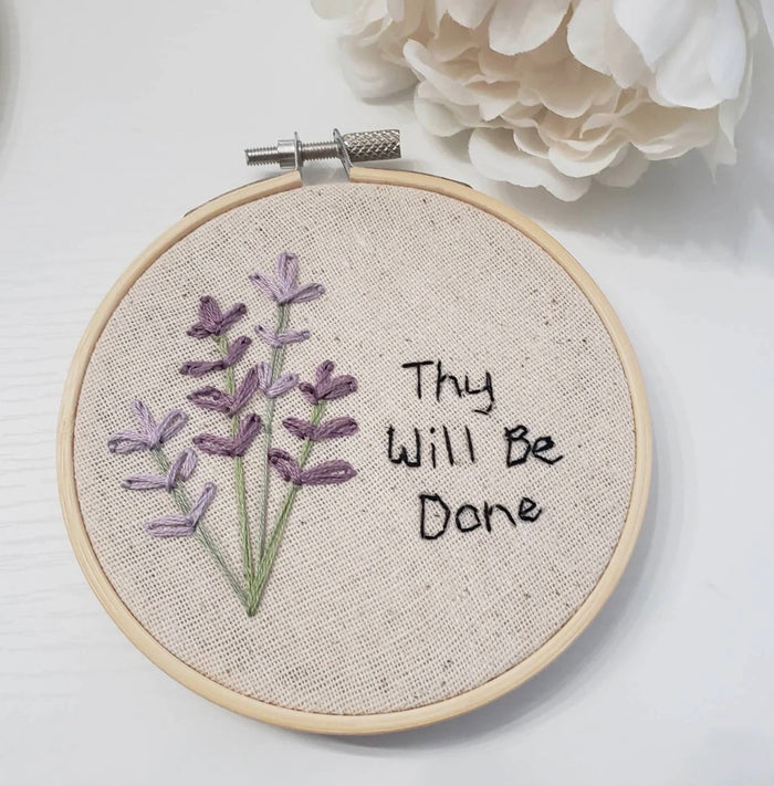 Embroidery hoop with lavender design and 'Thy Will Be Done' text on a white background